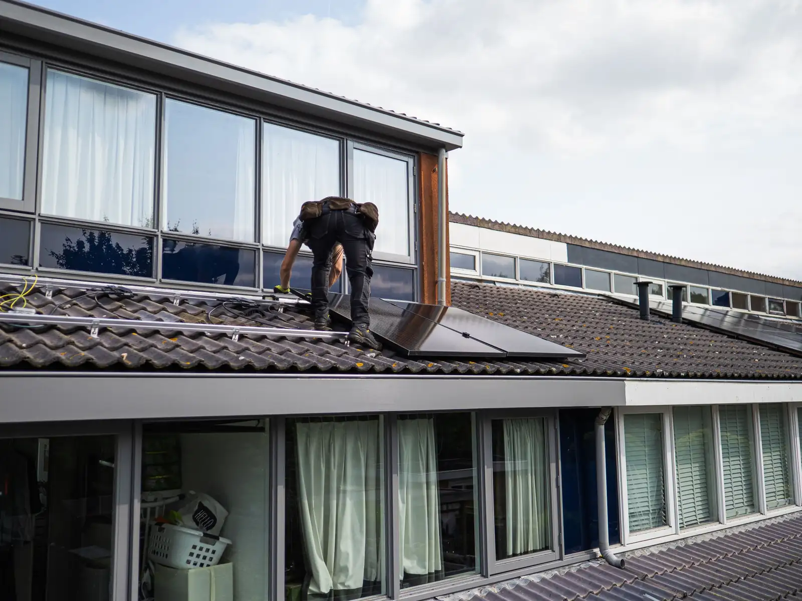 Monteur bei der Installation von Solarmodulen auf einem Ziegeldach